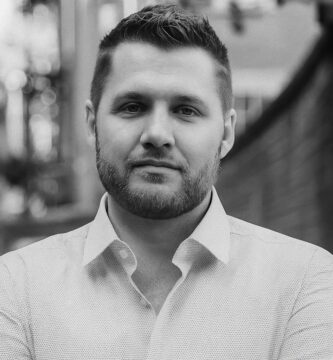 Ritratto in bianco e nero di Mark Manson, autore e blogger statunitense, noto per le sue frasi dirette su responsabilità personale, felicità e crescita emotiva – Il Meglio dei Libri